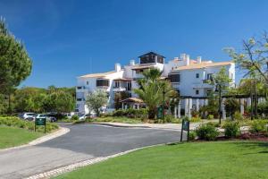 a road in front of a large white building at Pine Cliffs Suites in Albufeira