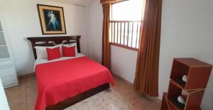 a bedroom with a red bed and a window at Alójate.Ica in Ica