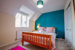 a bedroom with a bed and a blue wall at Guest Homes - Chichester Close Flat in Hereford