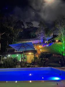 uma piscina azul com um guarda-chuva azul e um quintal em Estância dos Pássaros em Guaramiranga