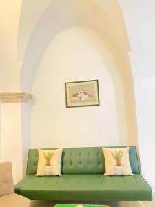 a green couch in a living room with a painting at A&A B&B Martina Franca in Martina Franca