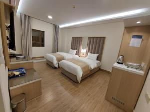ein Hotelzimmer mit 2 Betten und einem TV in der Unterkunft شقق كيان البستان للشقق المخدومة in Al-Hasa