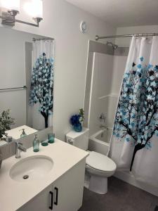 a bathroom with a toilet sink and a shower curtain at Entire4BedroomHomeKingParkingKitchenWasherDryerFastWiFi in Calgary