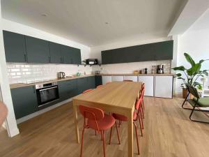a kitchen with a wooden table and red chairs at La Casa Calot in Angers