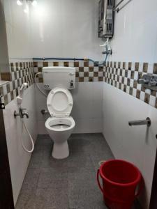 a bathroom with a toilet and a red bucket at Supritha Homestay Hampi in Hampi