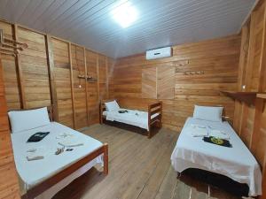 Habitación con 2 camas, paredes de madera y suelo de madera. en Amazon Seringal jungle Lodge en Careiro