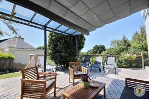 a patio with three chairs and a table and a large pergola at La maison de lannion in Lannion