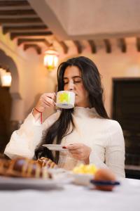a woman drinking from a cup of coffee at Riad Atlas Toyours in Marrakesh