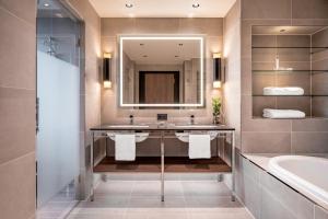 ein Bad mit einem Waschbecken und einem Spiegel in der Unterkunft Geneva Marriott Hotel in Genf