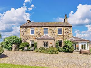 an old stone house with two chairs in the yard at 3 Bed in Kinglassie FF224 in Kinglassie