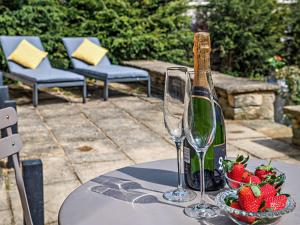 una botella de champán y un tazón de fresas sobre una mesa en 1 bed property in Lechlade 31912, en Lechlade 8 fotos más