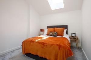 a bedroom with a bed with an orange blanket at Stylish Penthouse with outside balcony! in Bradford
