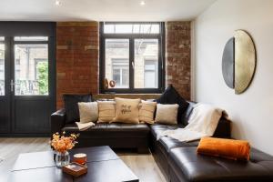 a living room with a black leather couch at Stylish Penthouse with outside balcony! in Bradford