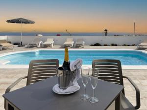 a table with a bottle of wine and glasses next to a pool at Villa Livia Oceanwiew Quiet Eco in Tías