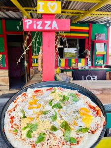 a pizza sitting on top of a pan on a table at Land of Promise - Reggae Escape in Zanderij