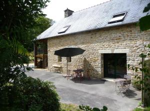 a stone building with a table and an umbrella at La maison des charretiers in Cohiniac