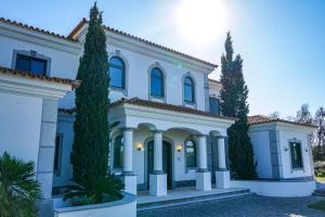 ein großes weißes Haus mit Bäumen davor in der Unterkunft Villa Algarve in Vila Nova De Cacela