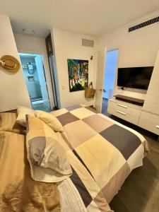 1 dormitorio con 1 cama y TV en Cimarron Suites Playa Parguito, en El Cardón