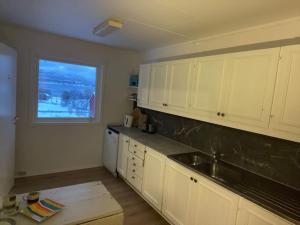 a kitchen with white cabinets and a window at Ivar and Sofies House in Tromsø