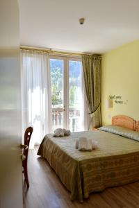 a bedroom with a bed and a large window at Hotel Saisera in Valbruna