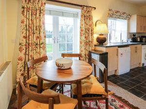 cocina y comedor con mesa de madera y sillas en The Stables, en Dumfries