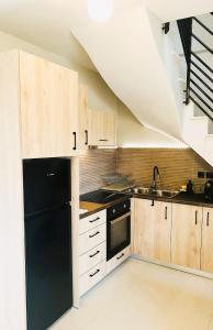 uma cozinha com um frigorífico preto e armários de madeira em athilia em Nikiana