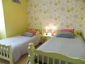 Duas camas individuais num quarto com paredes amarelas. em Les cerisiers 