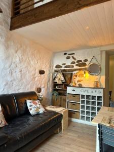 ein Wohnzimmer mit einem schwarzen Ledersofa und einem Herd in der Unterkunft Charmant duplex 2 chambres/terrasse in Prades