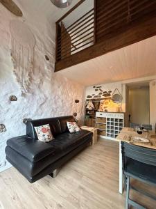 uma sala de estar com um sofá de couro preto e uma cozinha em Charmant duplex 2 chambres/terrasse em Prades