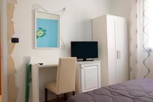 a bedroom with a desk with a television and a chair at B&B La Rosa Lampedusa in Lampedusa