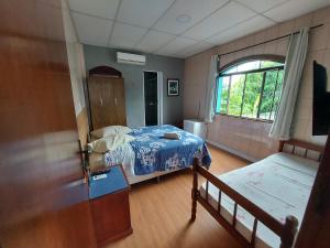 Habitación pequeña con cama y ventana en Pousada Casa Familia en Nova Iguaçu