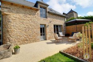 ein Steinhaus mit einer Terrasse mit Stühlen und einem Sonnenschirm in der Unterkunft La maison de victorine in Dinan