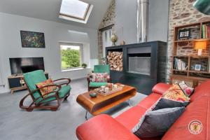 a living room with a red couch and chairs and a fireplace at La ritournelle in Pleslin-Trigavou