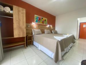 a bedroom with a large bed and a table at Kaliman Pousada in Ubatuba
