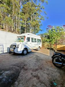 ein kleiner weißer Van neben einem Motorrad geparkt in der Unterkunft Wander Valley in Udagamandalam
