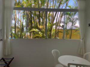 una ventana con mesa, sillas y palmeras en Kaliman Pousada, en Ubatuba