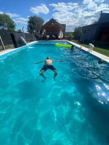 a man swimming in a pool of blue water at Casa Vip Pileta Climatizada Carlos Paz in Tanti
