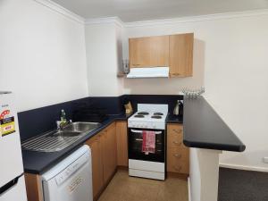 a small kitchen with a stove and a sink at Canberra City Accommodation in Canberra