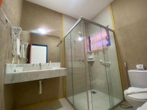 a bathroom with a shower and a sink and a toilet at Kaliman Pousada in Ubatuba