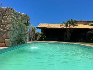 a swimming pool with a water fountain at Casa de Praia Com Piscina perto da praia in São João da Barra