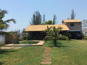 a house with a pool and a palm tree in the yard at Casa de Praia Com Piscina perto da praia in São João da Barra