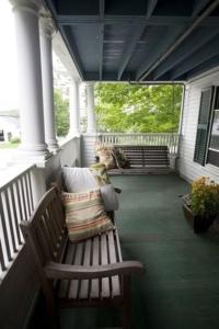 a dog sitting on a porch with a bench at The Monadnock Inn in Jaffrey
