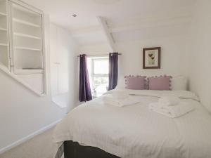 a white bedroom with a bed with towels on it at Blacksmiths Cottage in Newquay
