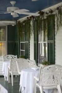 un grupo de mesas y sillas blancas en un porche en The Monadnock Inn, en Jaffrey