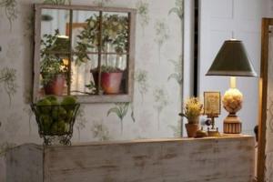 una mesa con lámpara, espejo y plantas en The Monadnock Inn en Jaffrey