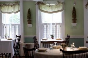 un comedor con mesas, sillas y ventanas en The Monadnock Inn, en Jaffrey