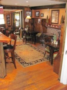 a living room with a table and a piano at The Monadnock Inn in Jaffrey