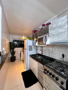 a kitchen with a stove and a white refrigerator at Apartamento decorado no Jardim Lancaster in Foz do Iguaçu