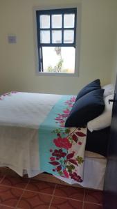 a bed with a comforter and a window in a room at Casinha do Peró in Cabo Frio