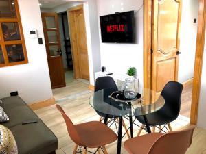 uma sala de estar com uma mesa de vidro e cadeiras em Family Apartment centro ciudad + Netflix em Cuenca